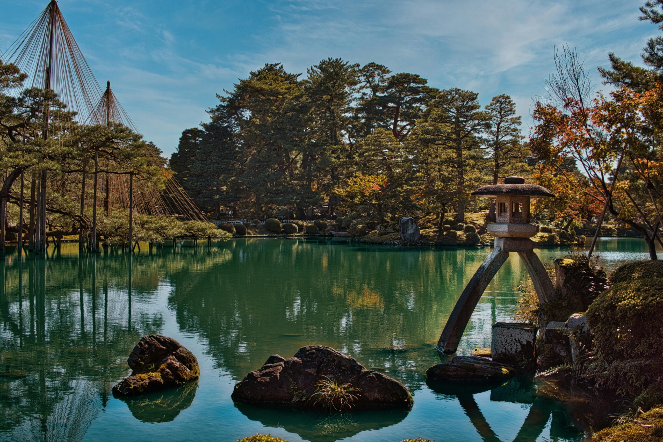 Ruhige Landschaft des Kenrokuen-Gartens mit traditioneller Laterne und ruhigem Teich in Kanazawa, Japan.